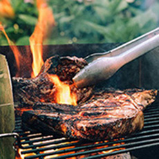 Close up of meat cooking over open flames on the grill 